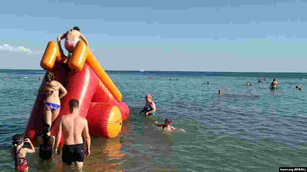 Та же ситуация наблюдается и у одного из пляжных развлечений. В очередь на бесплатную надувную горку отдыхающие дистанции не соблюдают. Корреспондент Крым.Реалии также не заметил, чтобы поверхности горки, за которые люди берутся руками, кто-либо дезинфицировал. О других пляжах Евпатории читайте тут