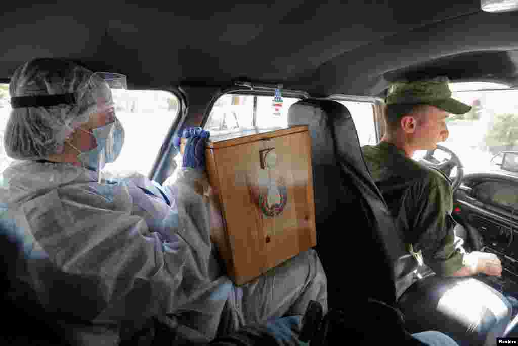 Член виборчої комісії, одягнений у захисний костюм, вирушає до місцевих жителів у Мінську під час президентських виборів у Білорусі