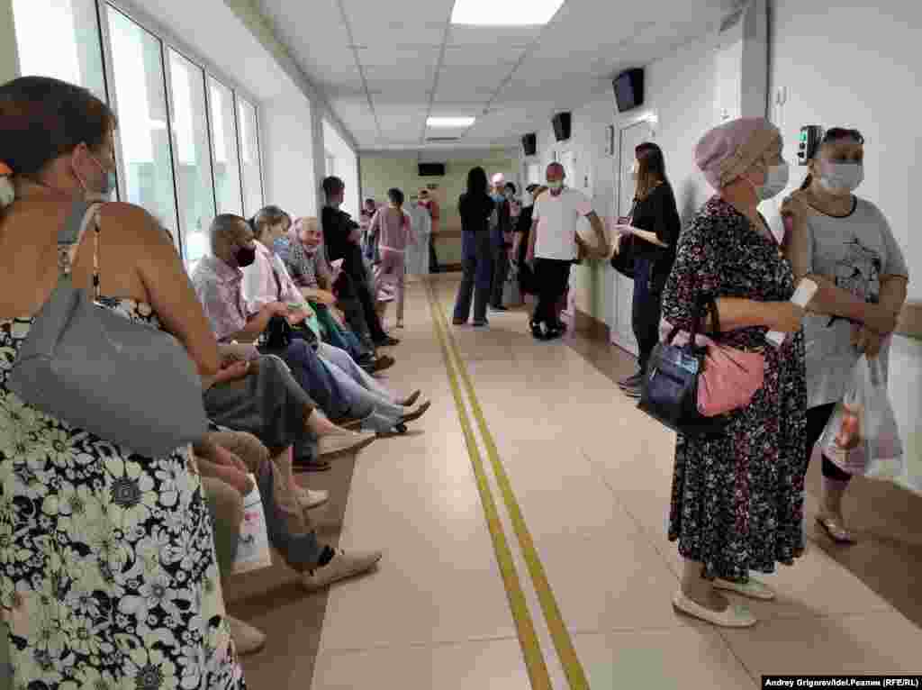 Здесь и следующие три снимка: очередь к терапевтам. Врачи принимают с двух в двух расположенных рядом кабинетах. Ещё до назначенная срока собирается общая очередь примерно из тридцати человек. 