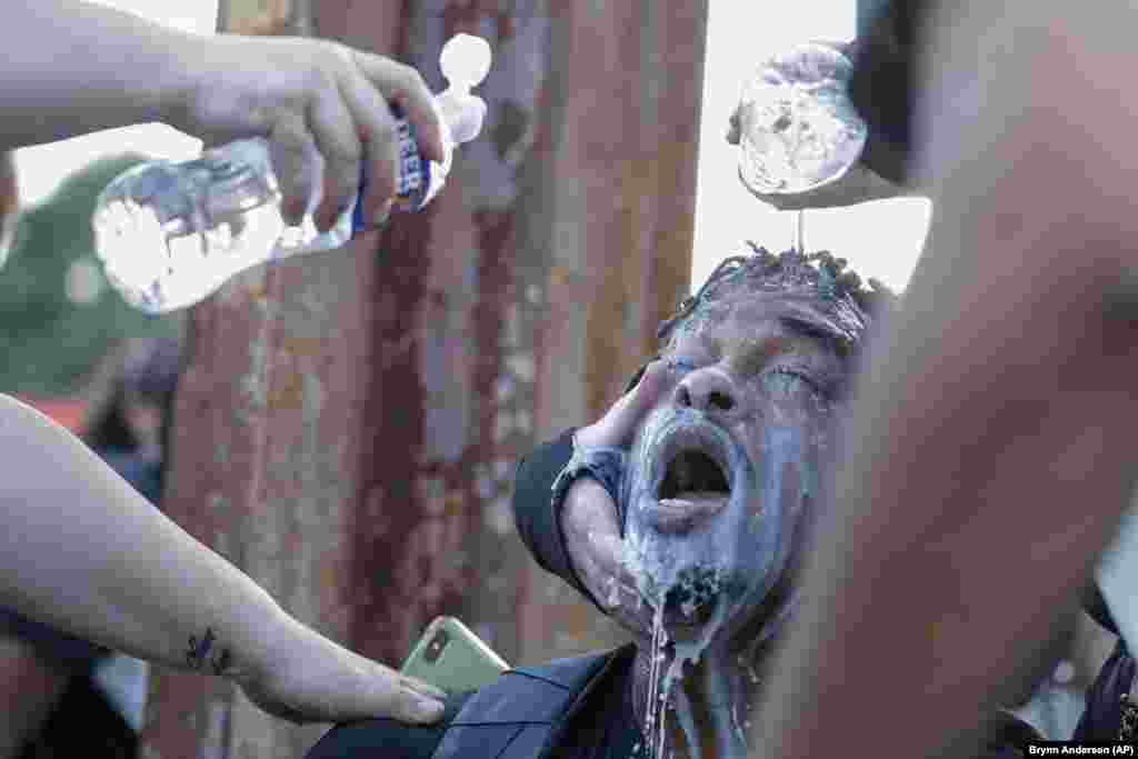 Обличчя протестувальника поливають водою після того, як поліцейські використали сльозогінний газ під час протестів біля ресторану швидкого харчування Wendy’s. Атланта, штат Джорджія, США