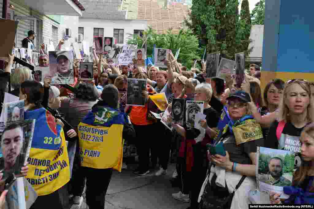 Люди утворили коридор і показують фотографії своїх близьких у полоні щойно звільненим в надії, що ті їх впізнають і можливо розкажуть якусь інформацію