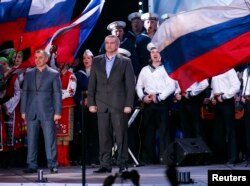 Владимир Константинов (слева) и Сергей Аксенов стоят на сцене во время оглашения предварительных результатов так называемого «референдума о присоединении к России». Симферополь, 16 марта 2014 года