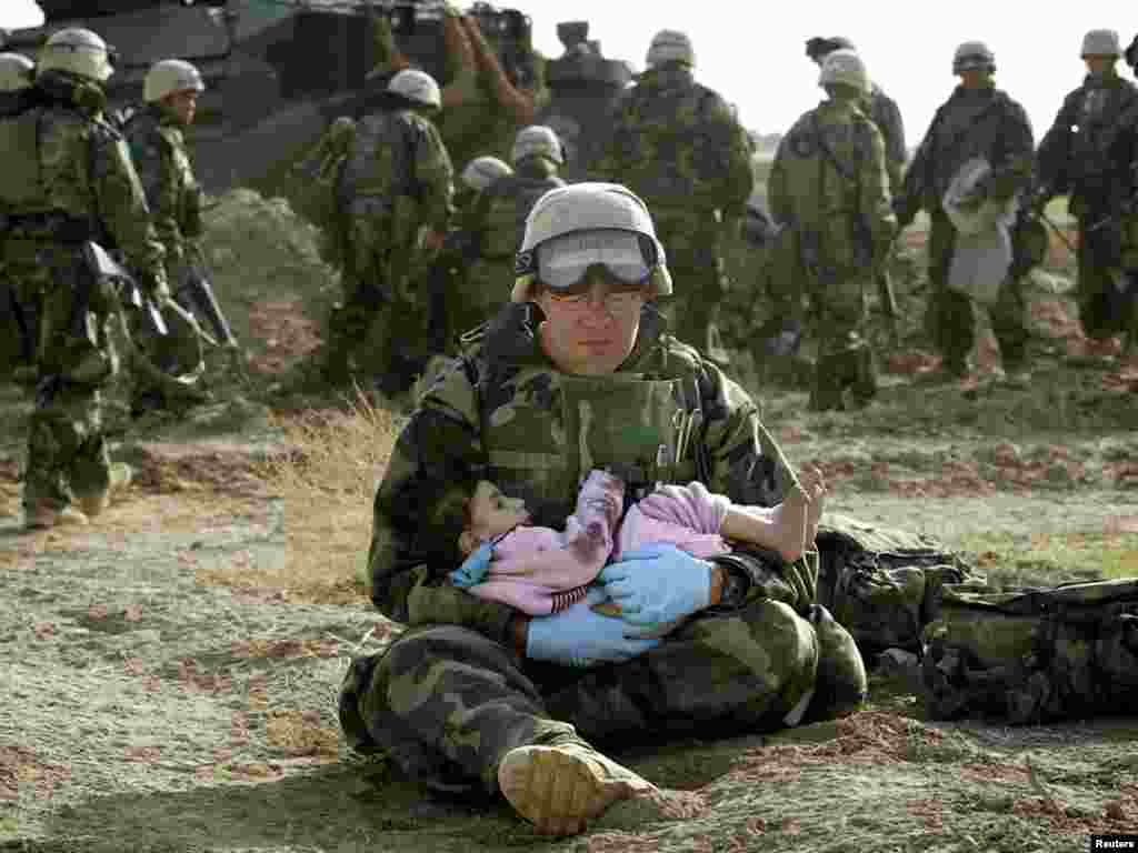 Irak, američki vojnik Richard Barnett sa ranjenim djetetom čeka na pomoć, 14.12.2003.