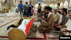 Mourners pray at the coffin of a victim killed during an attack on a prison in Taji -- one of two large-scale jailbreaks claimed by Al-Qaeda.