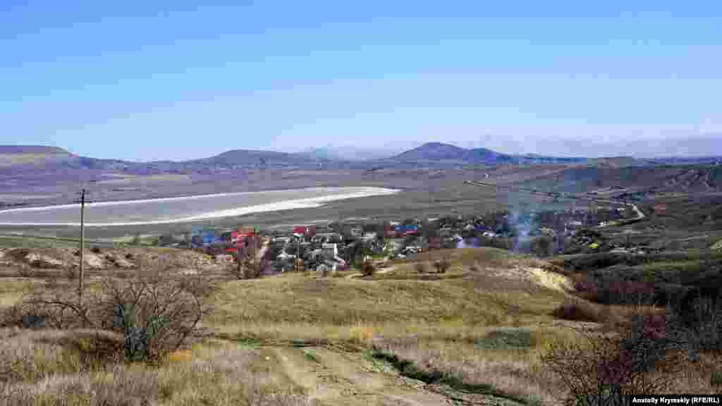 Вид на Баракольскую котловину с селом Наниково и пересыхающим озером Бараколь. Озеро находится на высоте всего 57 сантиметров над уровнем моря. До сих пор некоторые туристические справочники утверждают, что зимой и в межсезонье Бараколь полноводное, но на самом деле это не так – несколько последних лет и зимой, и летом воды там нет совсем, а на месте озера только белеет выступившая соль