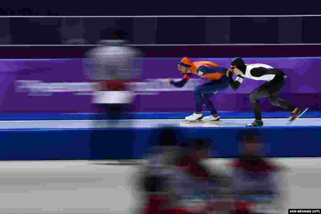 Катание на коньках: голландец Кьелд Нейс (слева) и японец Такура Ода соревнуются во время мужских соревнований на дистанции 1500 метров. Нейс получил золотую медаль