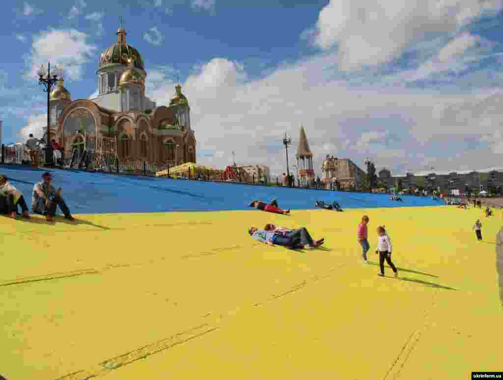 Частину бетонної набережної Дніпра в Оболонському районі столиці розмалювали в синьо-жовті кольори. На прапор площею у 1750 квадратних метрів пішло 500 літрів фарби і понад 40 тисяч гривень. Тепер це – найбільший державний прапор України. Київ, 16 червня 2014 року