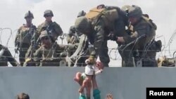 Немовля передають американським військовим через загороджувальну стіну аеропорту Кабула під час евакуації людей, які хочуть втекти від талібів. Афганістан, 19 серпня 2021 року.