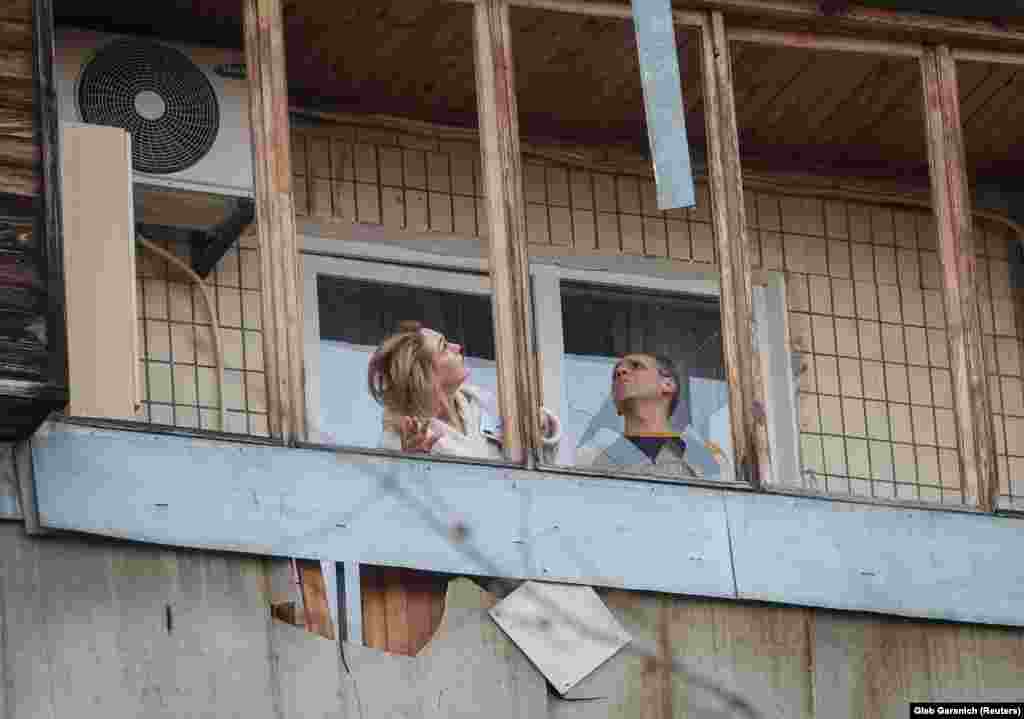 Мешканці багатоповерхівки оглядають руйнування на своєму балконі.Керівництво Росії заперечує, що російська армія під час повномасштабної війни завдає цілеспрямованих ударів по цивільній інфраструктурі міст і сіл України, убиваючи цивільне населення і руйнуючи лікарні, школи, дитячі садочки, об’єкти енергетики та водозабезпечення