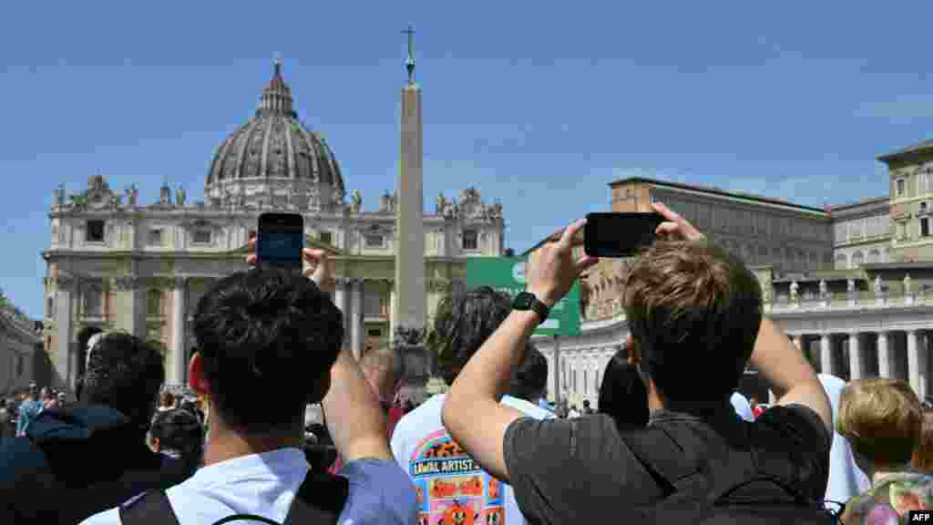Луѓе фотографираат додека се собираат во Ватикан по веста за смртта на папата.