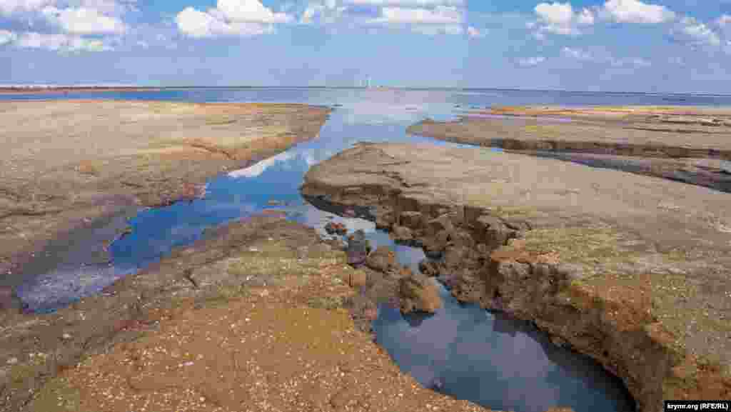 Вода сохранилась лишь в восточной части озера. На переднем плане – птичьи «ванны». Вдалеке виднеются ветрогенераторы функционирующей Восточно-Крымской ветряной электростанции