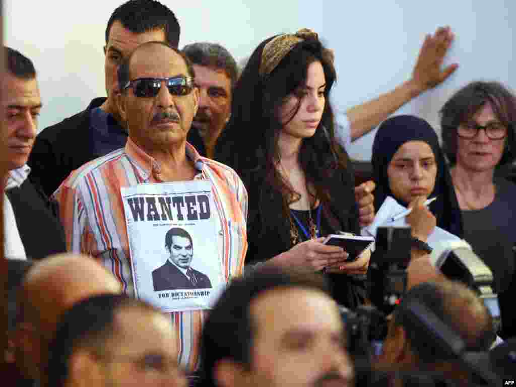 Человек с плакатом "разыскивается" и фотографией экс-президента Туниса Зин эль-Абидина Бен Али - один из зрителей на заочном судебном процессе против бывшего руководителя страны и его супруги, которые бежали из Туниса в Саудовскую Аравию после первой из революций "арабской весны". Решением суда от 20 июня 2011 года Бен Али был приговорен к 35 годам тюрьмы и штрафу в 40 миллионов евро. Спустя год Военный трибунал Туниса приговорил Бен Али к пожизненному заключению за убийство демонстрантов во время подавления восстания в стране. Совсем незадолго до этого, в 2009-м, Бен Али набрал на президентских выборах 89,62% голосов избирателей.