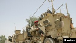 An Iraqi soldier patrols near U.S. military armoured vehicles as the U.S. Army prepares to leave a military base in Mahmudiyah in July.
