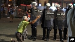 Čovek koji kleči ispred kordona policije tokom protesta u Beogradu, 28. juna 2025.