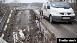 Автомобіль переїздить зруйнований війною міст в Луганській області, березень, 2015 року