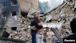 რუსეთის მასირებულ შეტევას გადარჩენილი კიეველები განადგურებული სახლის ფონზე. 2025 წლის 17 ივნისი