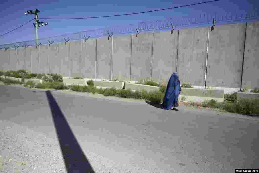 Женщина в бурке на дороге у бывшей американской военной базы в Баграме, 1 июля. Бурка &mdash; это накидка на все тело с сеткой для лица. Некоторые мусульмане-фундаменталисты интерпретируют спорные фрагменты Корана как требующие от женщин полностью скрывать лицо и тело от посторонних глаз&nbsp;