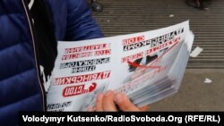 Чоловік роздає листівки з агітацією проти кандидата Олександра Дубінського