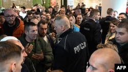 Польські поліцейські розмовляють з українцями, коли вони збираються перед закритим пунктом паспортної служби України у Варшаві, Польща, 24 квітня 2024 року