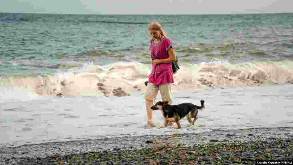 Октябрь 2020 года. Жительница Алушты вышла на променад во время шторма. Несмотря на середину осени, температура держится на уровне 21-23°C. Температура воды в Черном море сохраняется на том же уровне