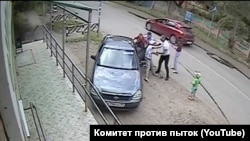 Полицейские силой пытаются посадить в машину Игоря Скоротягу и его мать. Скриншот из видео, опубликованного в ютуб-канале "Комитета против пыток"