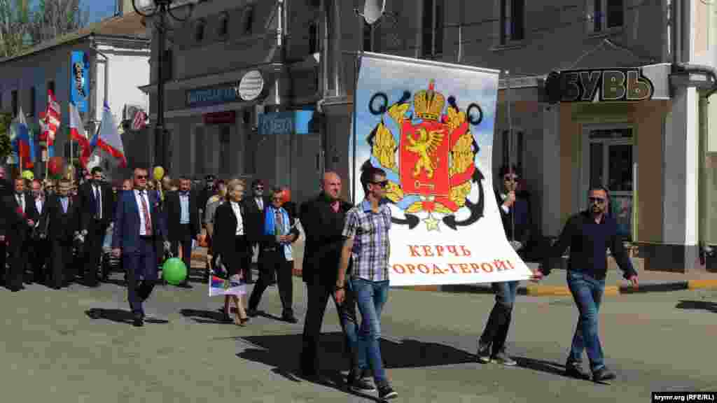 Во главе колонны несут плакат с гербом Керчи. За ним следуют представители подконтрольной Кремлю администрации города. 
