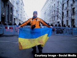 Сергій Нужненко тримає в руках заплямований кров’ю прапор, в який був загорнутий 1 грудня