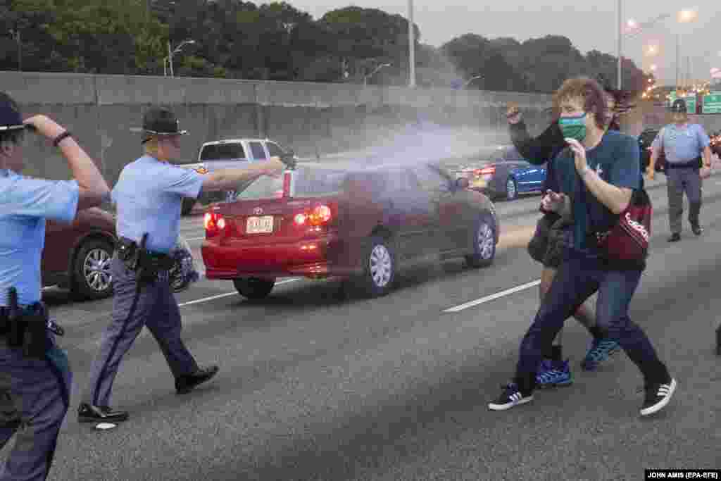 Правоохоронець використовує проти демонстрантів перцевий аерозоль після того, як група протестувальників вийшла на міждержавне шосе після протесту біля ресторану швидкого харчування Wendy’s. Атланта, штат Джорджія, США