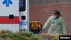 یکی از اعضای کادر درمانی بیمارستان سنوینسنت در ایالت ماساچوست در حال ضدعفونی کردن آمبولانس