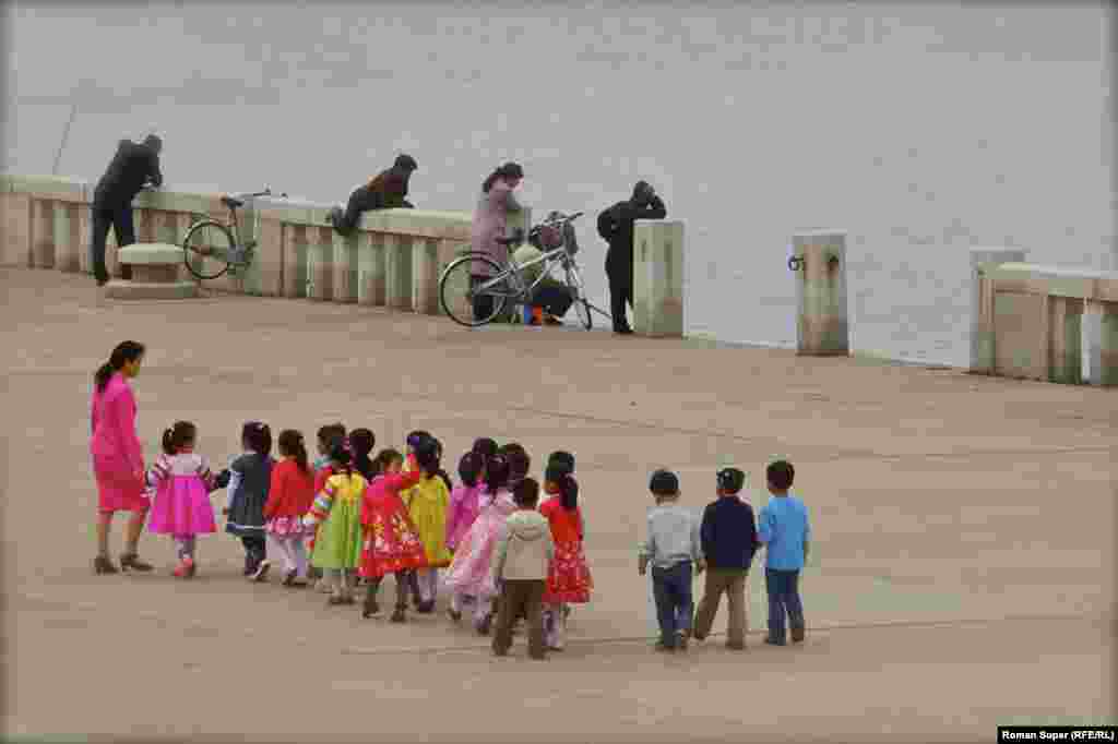 Детский сад на прогулке вдоль набережной. Зачем мужчина пытается прыгнуть в воду – мы не знаем