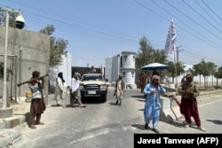 Taliban fighters stand guard at an entrance gate outside the Interior Ministry in Kabul on August 17. The armed militants are a common sight in the capital.