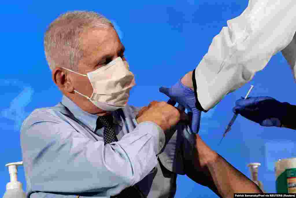 5 декабря в России, 8-го в Великобритании, 14-го в США и 27-го в ЕС началась вакцинация от COVID-19. На конец года в мире было уже 4 вакцины, одобренные на международном уровне.  При том, что российский оперативный штаб за период с апреля по октябрь насчитал только 28,2 тысячи смертей от коронавируса, в России за эти семь месяцев умерли на 120 тысяч человек больше, чем в среднем за этот период в последние пять лет. Не все эти так называемые "избыточные" смерти вызваны непосредственно коронавирусной инфекцией, но они с ней связаны: система здравоохранения во всем мире перегружена. На фотографии главный инфекционист США Энтони Фаучи получает 22 декабря прививку компании Moderna. (Patrick Semansky/Pool via REUTERS)