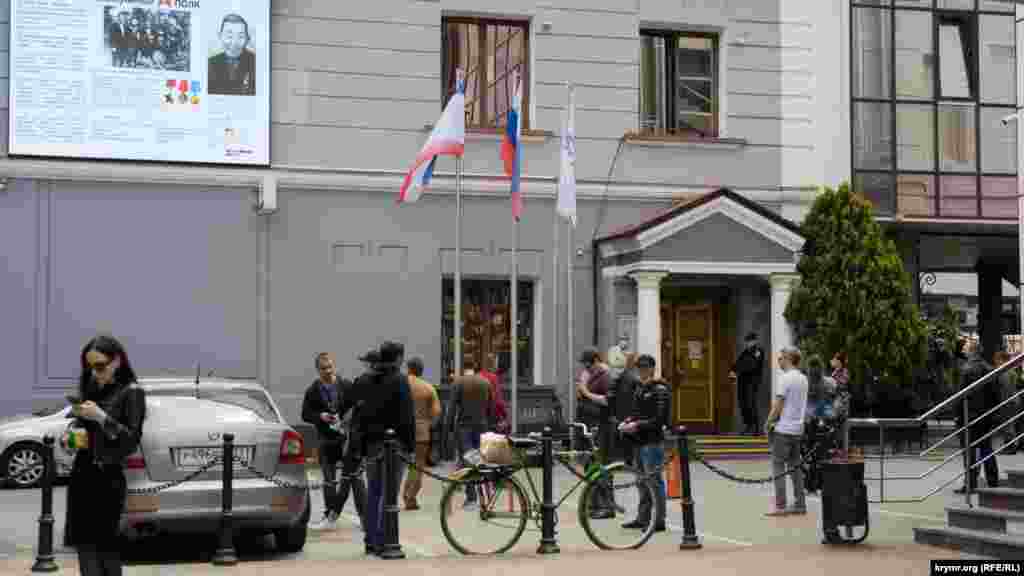 Очередь перед отделением банка «Россия» на проспекте Кирова. Чтобы люди не скучали, им транслируют на большой экране, установленном на фасаде здания, документальный «Бессмертный полк»