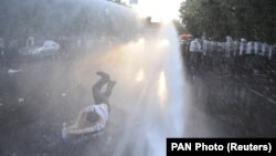 Струи из полицейского водомета сбивают с ног участника протеста в Ереване, 23 июня 2015 года