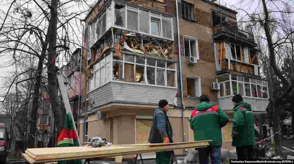 Пошкоджений російським обстрілом житловий будинок у Запоріжжі. На місці працюють комунальні служби: закривають пошкоджені вікна