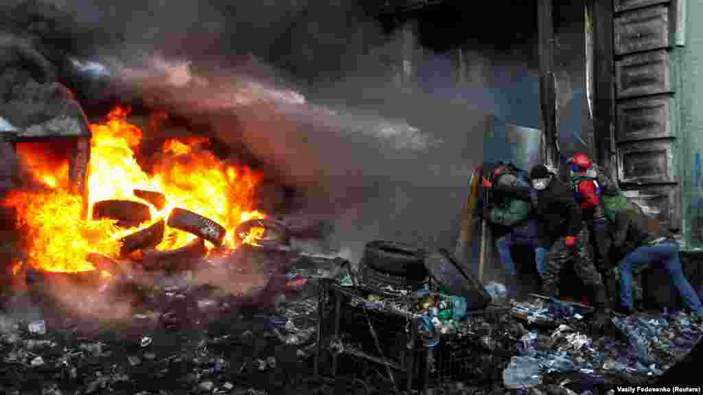 Революція гідності, Київ, січень 2014 року. Протести в Україні почалися після того, як президент Віктор Янукович вирішив згорнути процес євроінтеграції України на користь  зближення із Росією. В результаті протестів, що тривали три місяці, Янукович втік до Росії, а до влади в Україні прийшли сили на чолі з Петром Порошенком, який переміг на президентських виборах. Події Майдану в Кремлі назвали державним переворотом, що стало тригером для окупації Криму та розв'язання багаторічного збройного протистояння на Донбасі. Ця війну триває донині