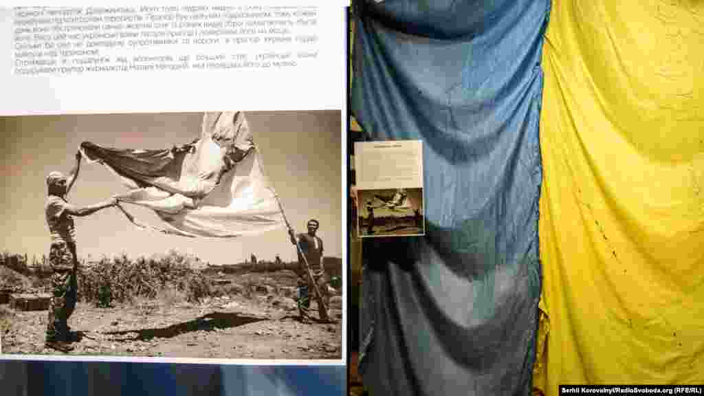 «Прапор». Історія, що відкриває виставку «Історії з війни», і розповідає про 17-й окремий батальйон територіальної оборони Кіровоградської області. Бійці підрозділу брали участь у бойових діях в таких населених пунктах, як Щастя, Красноталівка, Дебальцеве. Наразі батальйон захищає місто Дзержинськ. Прапор, що експонується, бійці батальйону встановили на териконі поблизу міста. Його було чудово видно з боку Горлівки, яка перебуває під контролем сепаратистів. Прапор був багаторазово обстріляний, проте кожен раз українські воїни латали його та повертали на місце