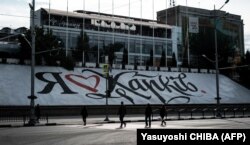 Люди переходять дорогу в Харкові біля банеру з написом «Я люблю Харків», 20 вересня 2022 року