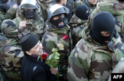 A Georgian woman holding flowers smiles as special forces leave without bloodshed outside the presidential residence of Eduard Shevardnadze on November 22, 2003.