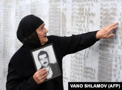 Грузинська жінка із фотографію свого родича біля пам'ятника жертвам грузинсько-абхазької війни 1992–1993 років. Тбілісі, 27 вересня 2009 року