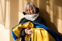 Тетяна Борисенко тримає в руках український прапор, який їй вдалося таємно ховати від сепаратистів протягом усього полону. На ньому – підписи 12 людей, разом з якими вона опинилася в ув'язненні. Борисенко була військовим медиком добровольчого батальйону «Айдар» і опинилася в полоні у вересні 2015 року