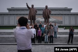 Туристи позують на тлі статуй північнокорейських політичних лідерів, Пхеньян