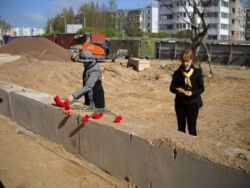 2011 год, внучки погибших в лагере солдат возлагают цветы на месте строительства