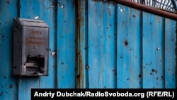 Вулиця Шевченка, 2, жив Шевченко А.Г. На фото – посічені осколками ворота до подвір’я в центрі села. Вказувати біля адреси ще й прізвище господаря – це була місцева традиція