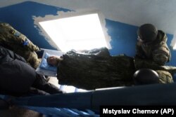 Українські військовослужбовці і цивільна особа несуть пораненого чоловіка, який зазнав поранення під часу обстрілу військовими Росії. Маріуполь, 3 березня 2022 року. Фото Мстислава Чернова