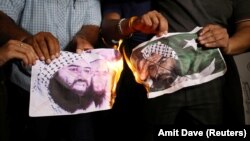 Ljudi pale slike Masooda Azhara, vođe pakistanske militantne grupe Jaish-e-Mohammad, dok slave odluku odbora Vijeća sigurnosti UN-a da Azhara stavi na crnu listu, u Ahmedabadu, Indija, maj 2019. godine