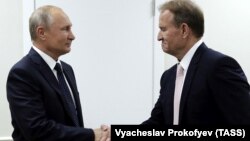 Повʼязаний з Кремлем колишній депутат Верховної Ради України Віктор Медведчук (праворуч) тисне руку президенту РФ Володимиру Путіну