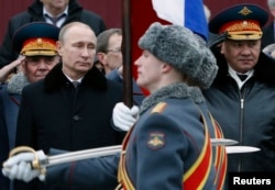 Russian President Vladimir Putin (left) and Defense Minister Sergei Shoigu (right) watch honor guards pass by as they attend a wreath-laying ceremony to mark the Defender of the Fatherland Day at the Tomb of the Unknown Soldier near the Kremlin on February 23.
