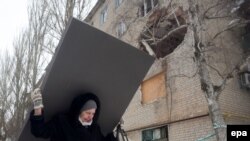 Жінка несе будівельний матеріал після обсрілів у Авдіївці, 3 лютого 2017 року