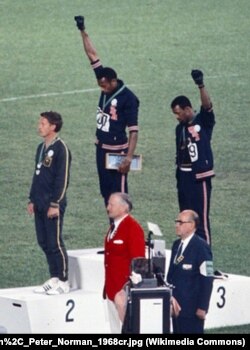 Томмі Сміт і Джон Карлос підняли вгору руку в чорній рукавичці в знак протесту проти расової дискримінації в США.